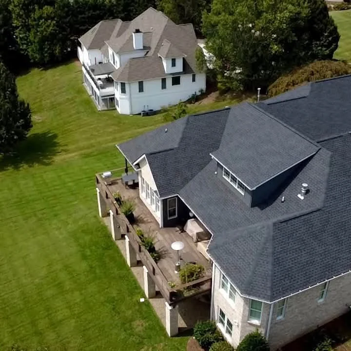 Aerial project photograph of dark shingle roofing across a home with intersecting gables, dormers and roof valleys.